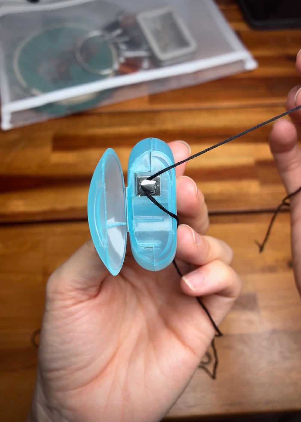 A close-up showing how to use a dental floss container blade to safely cut 6-strand embroidery thread while travelling.